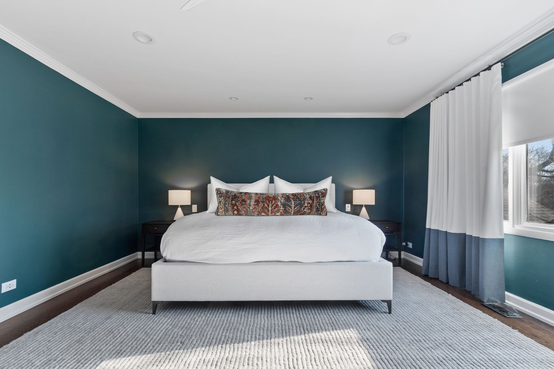 A bedroom with blue walls and a white bed.