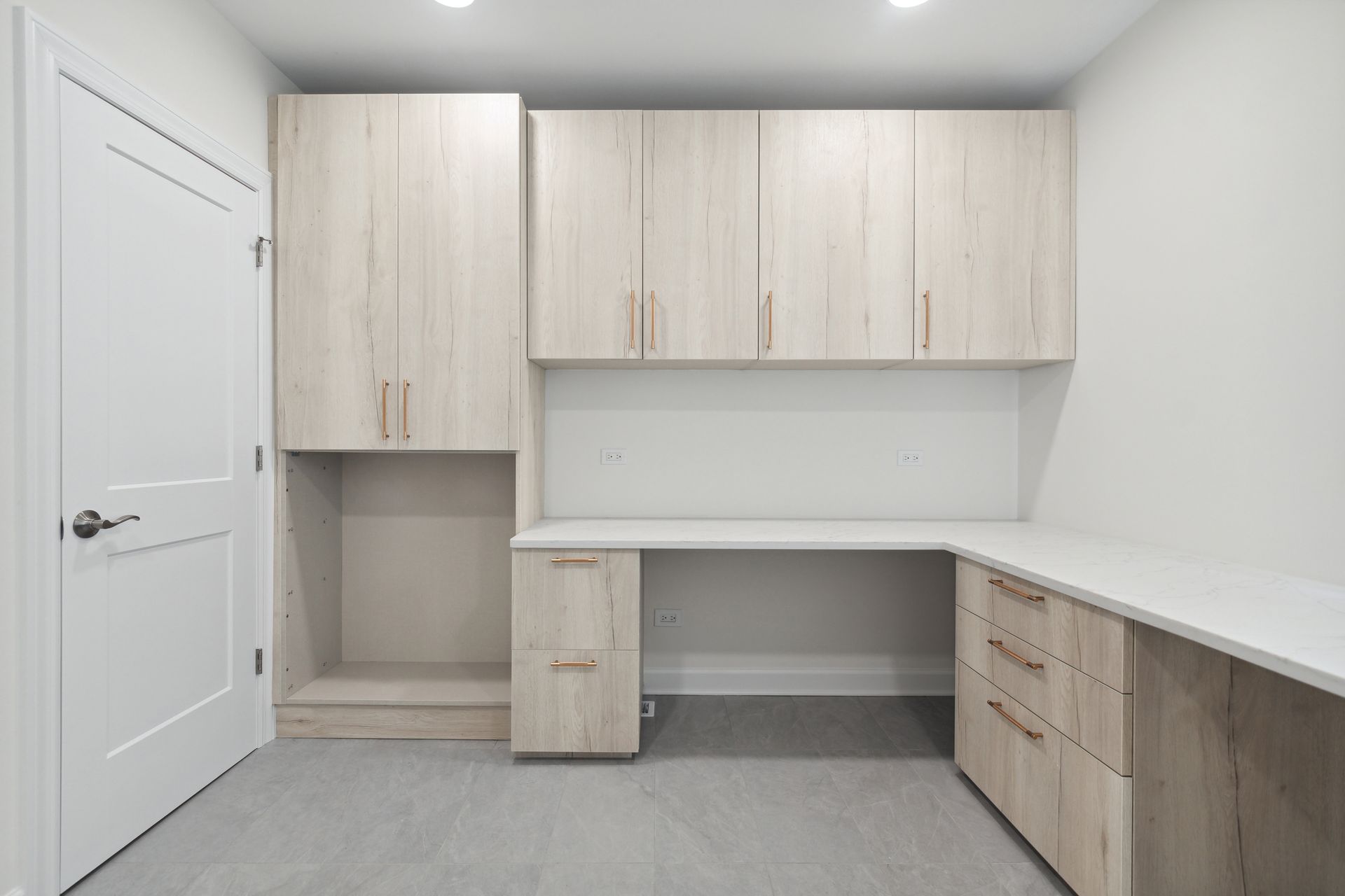 A room with a desk , cabinets , drawers and a door.