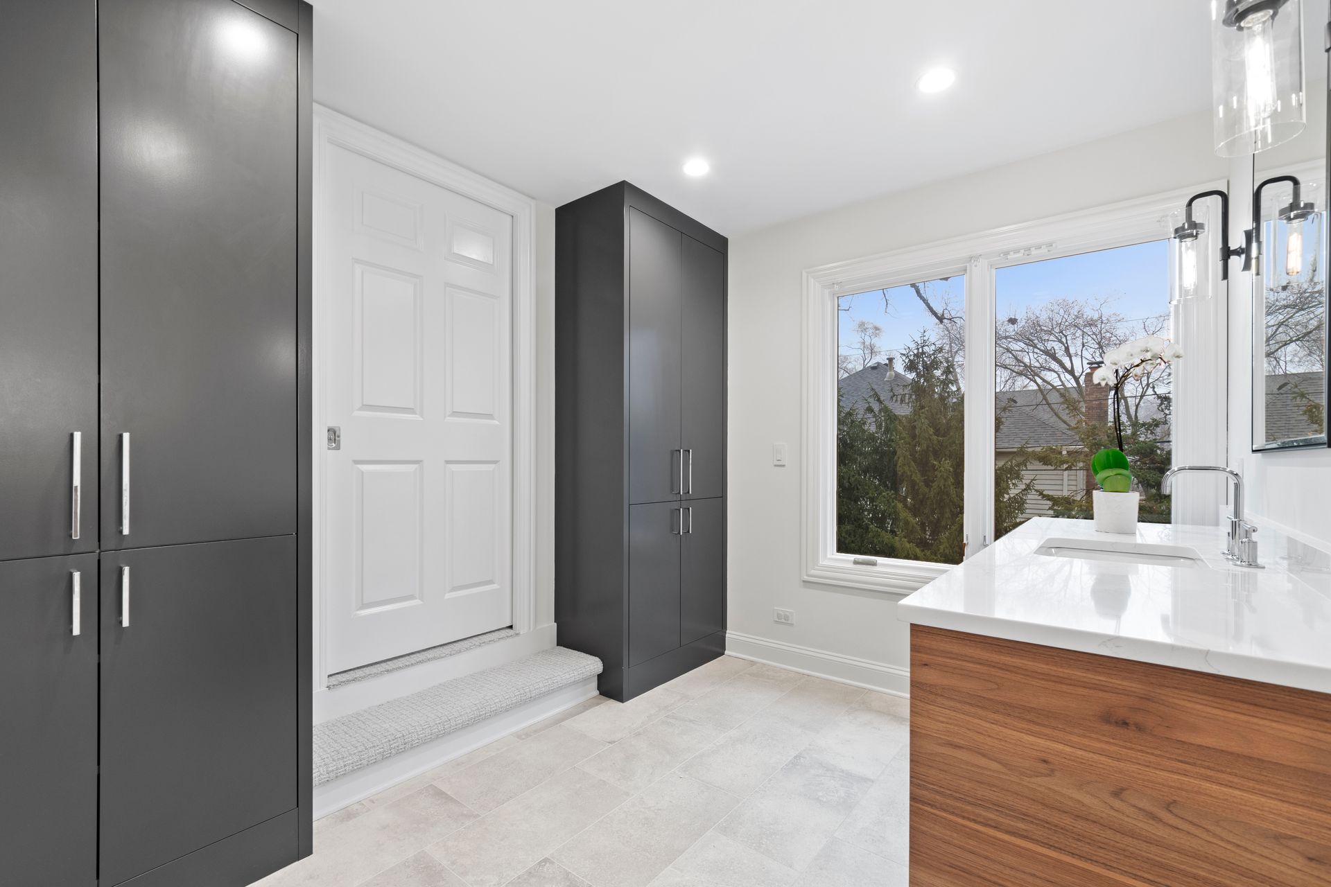 A bathroom with a sink , cabinets , and a window.