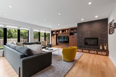 A living room with a couch , chair , fireplace and television.