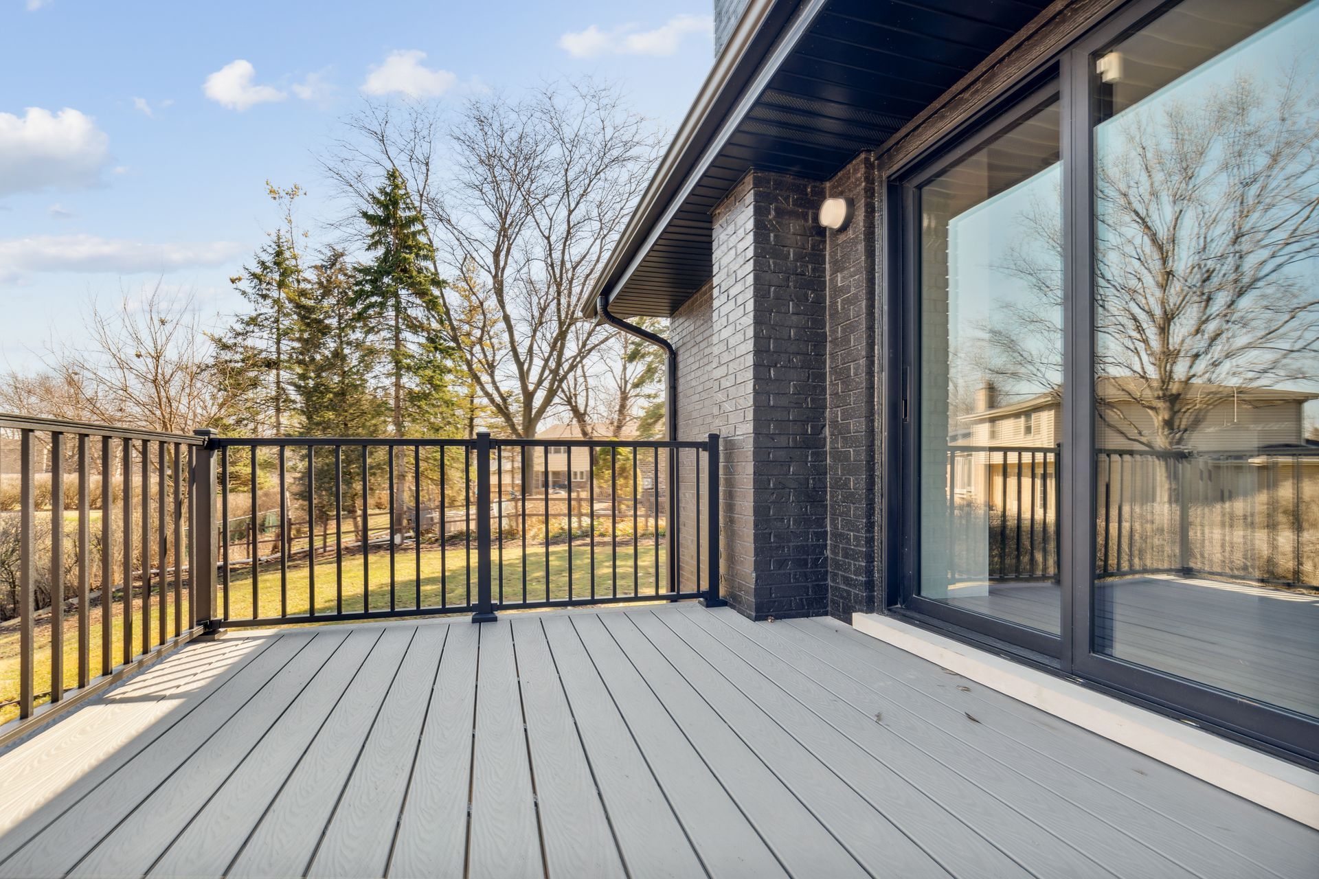 An empty deck with a railing and sliding glass doors.