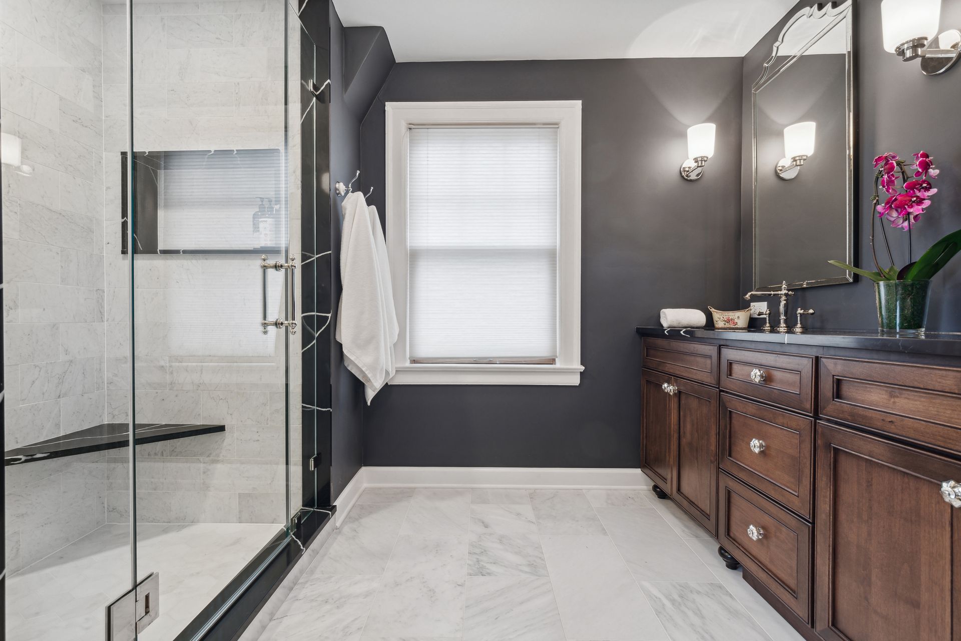 A bathroom with a walk in shower , sink , and mirror.
