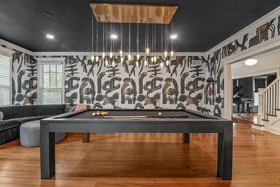 A pool table in a living room with a chandelier hanging from the ceiling.