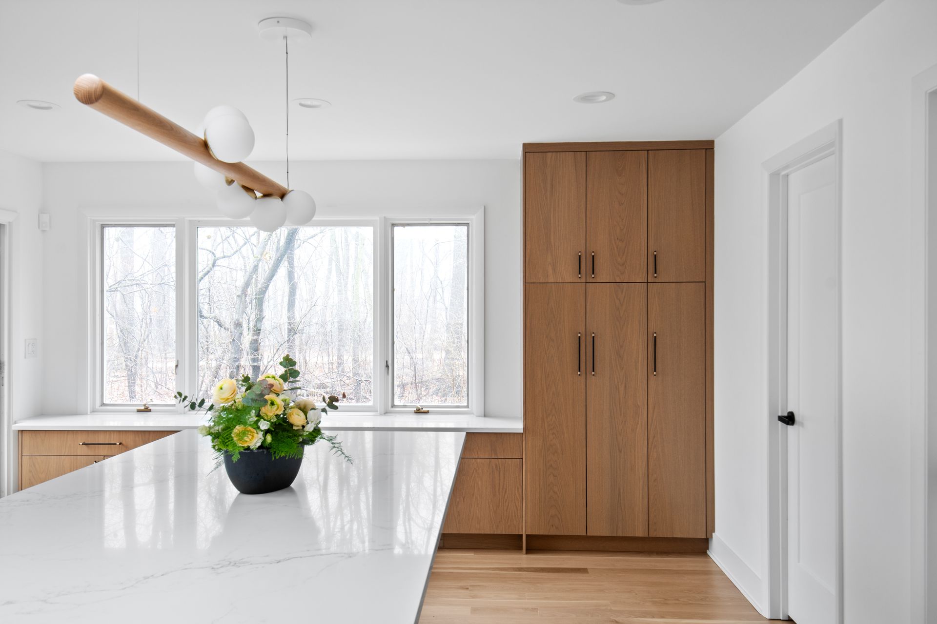 There is a vase of flowers on the counter in the kitchen.