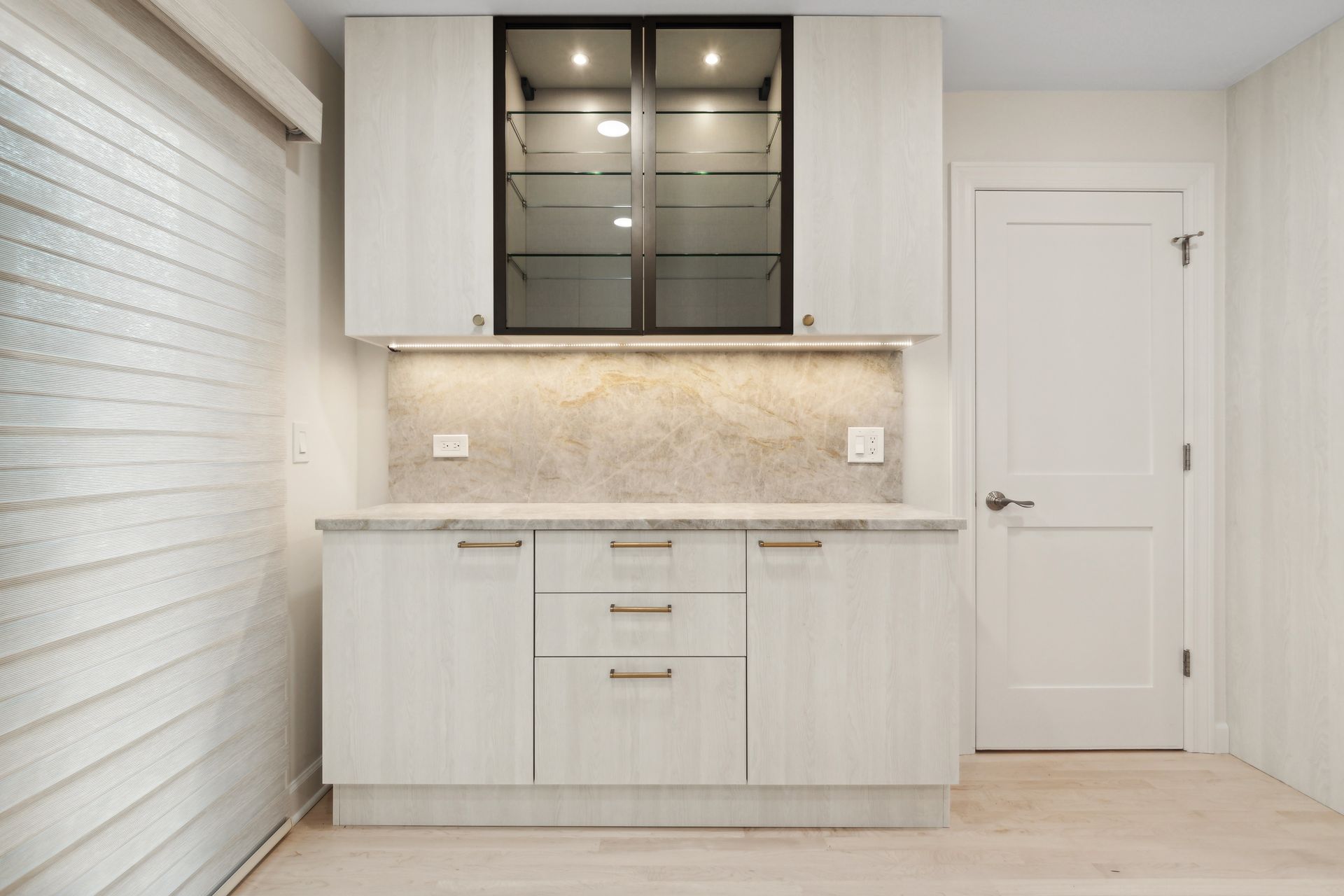 A kitchen with white cabinets and a glass door