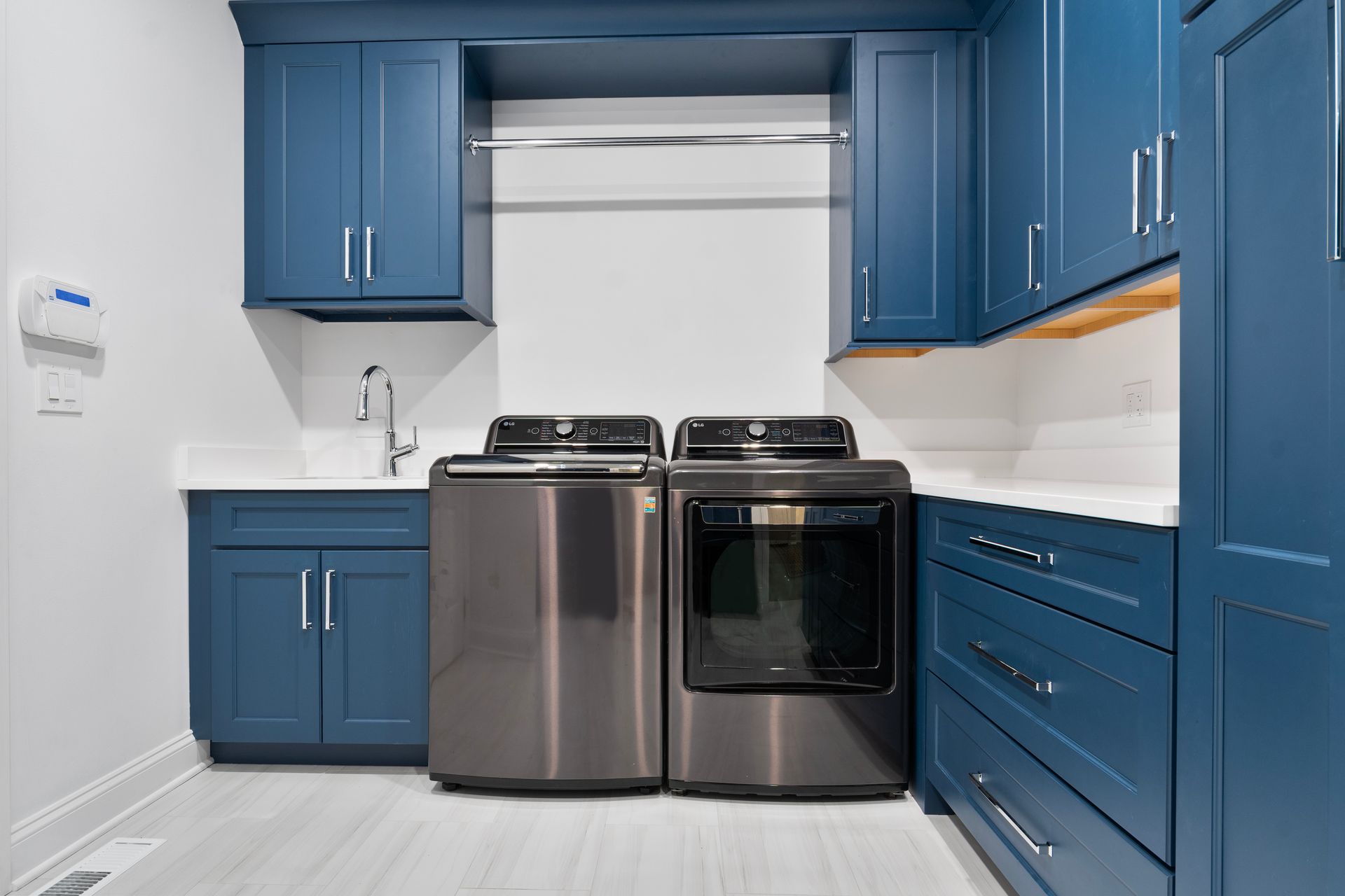 A laundry room with blue cabinets and stainless steel appliances.