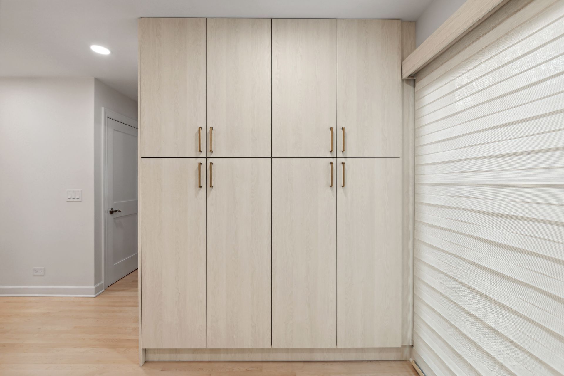 A room with a lot of cabinets and a window with blinds.