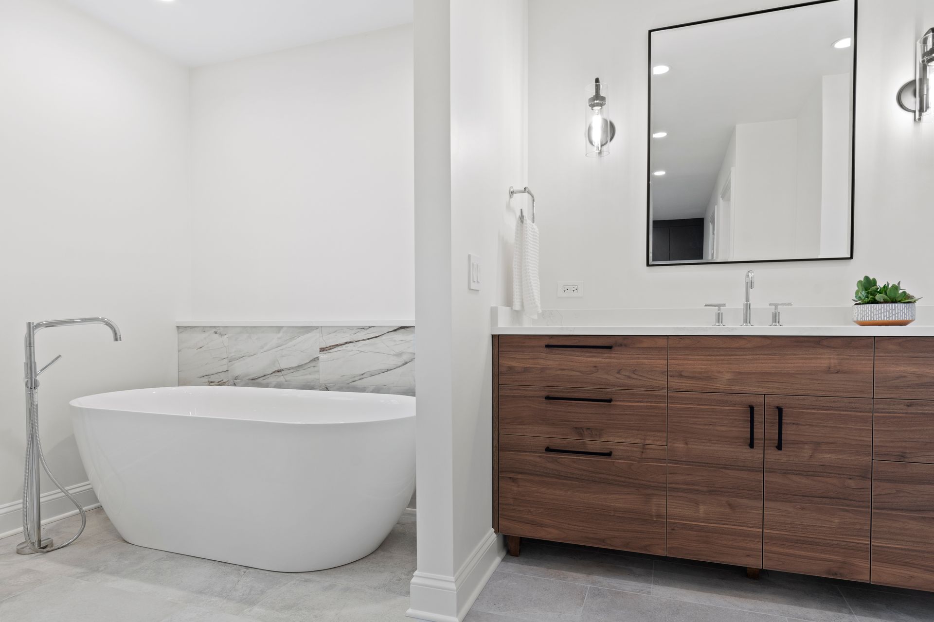 A bathroom with a bathtub , sink and mirror.