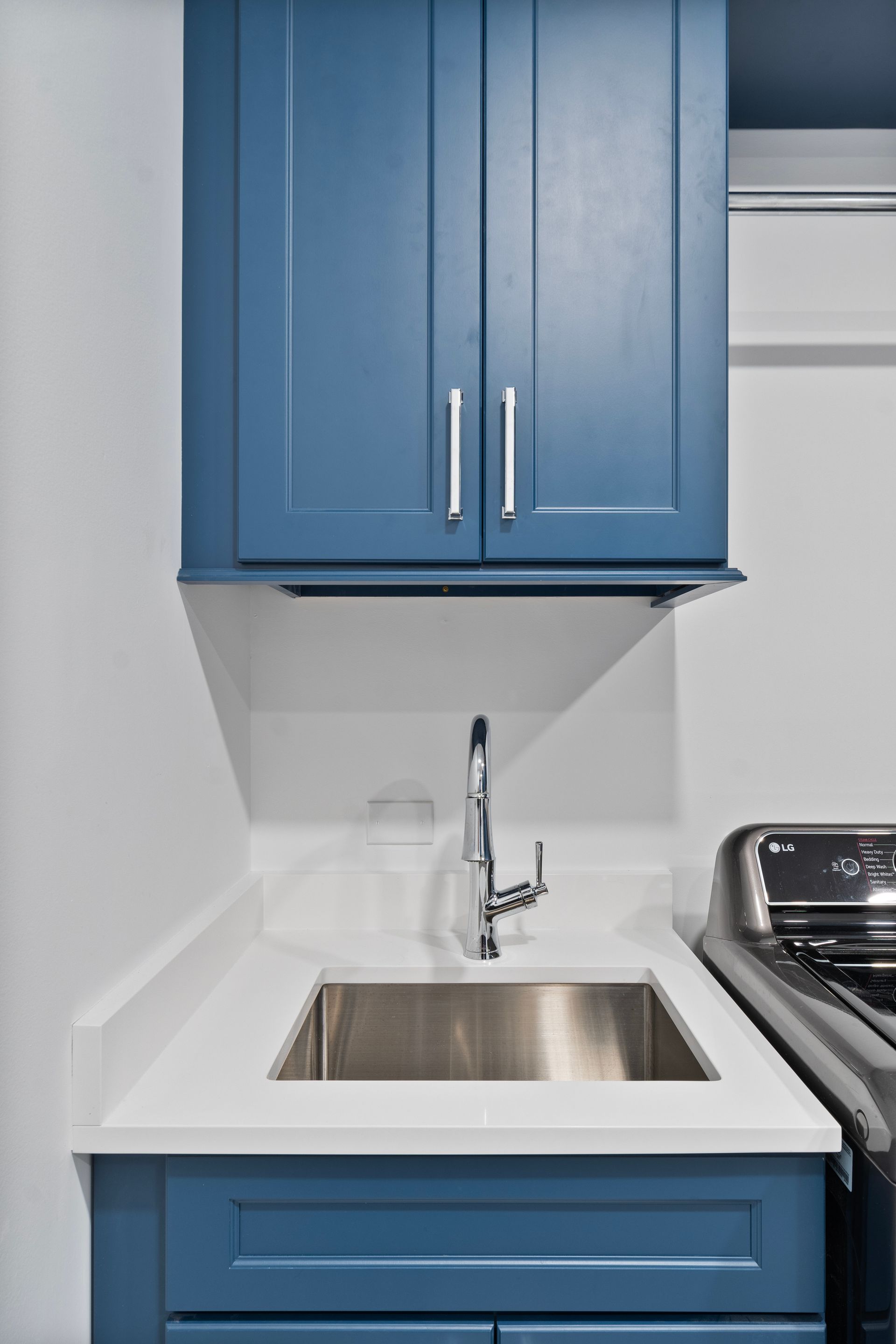 A kitchen with blue cabinets and a stainless steel sink.