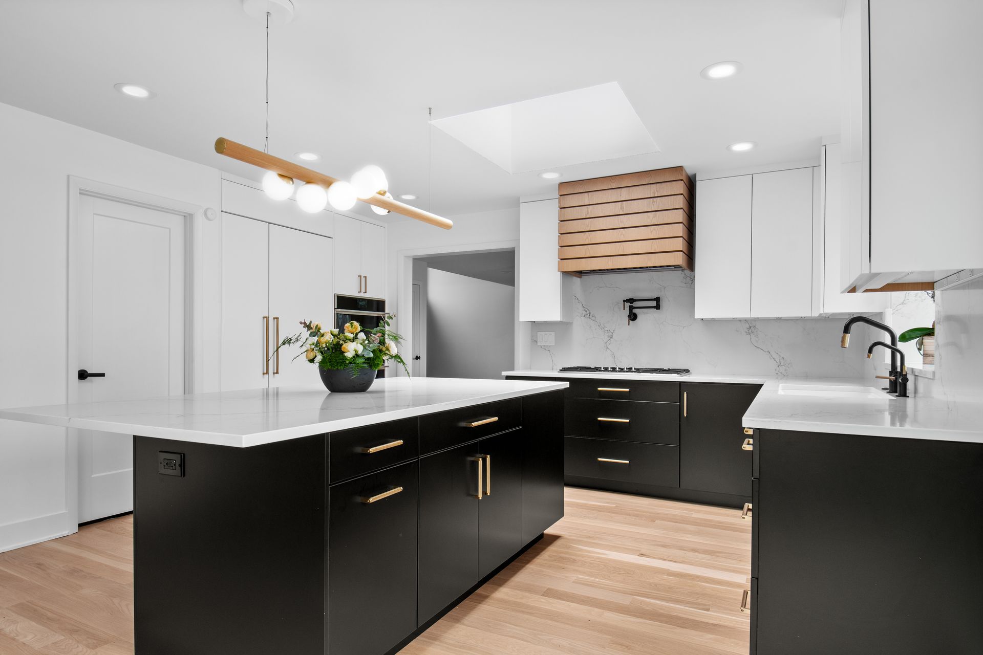 A kitchen with black cabinets and white counter tops and a large island.