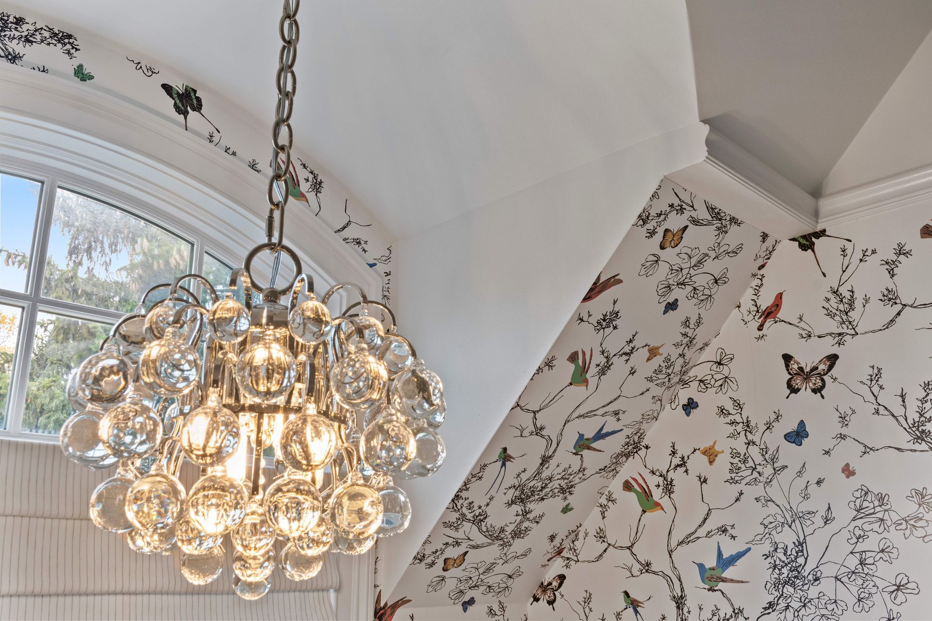 A chandelier is hanging from the ceiling in front of a wall with butterflies on it