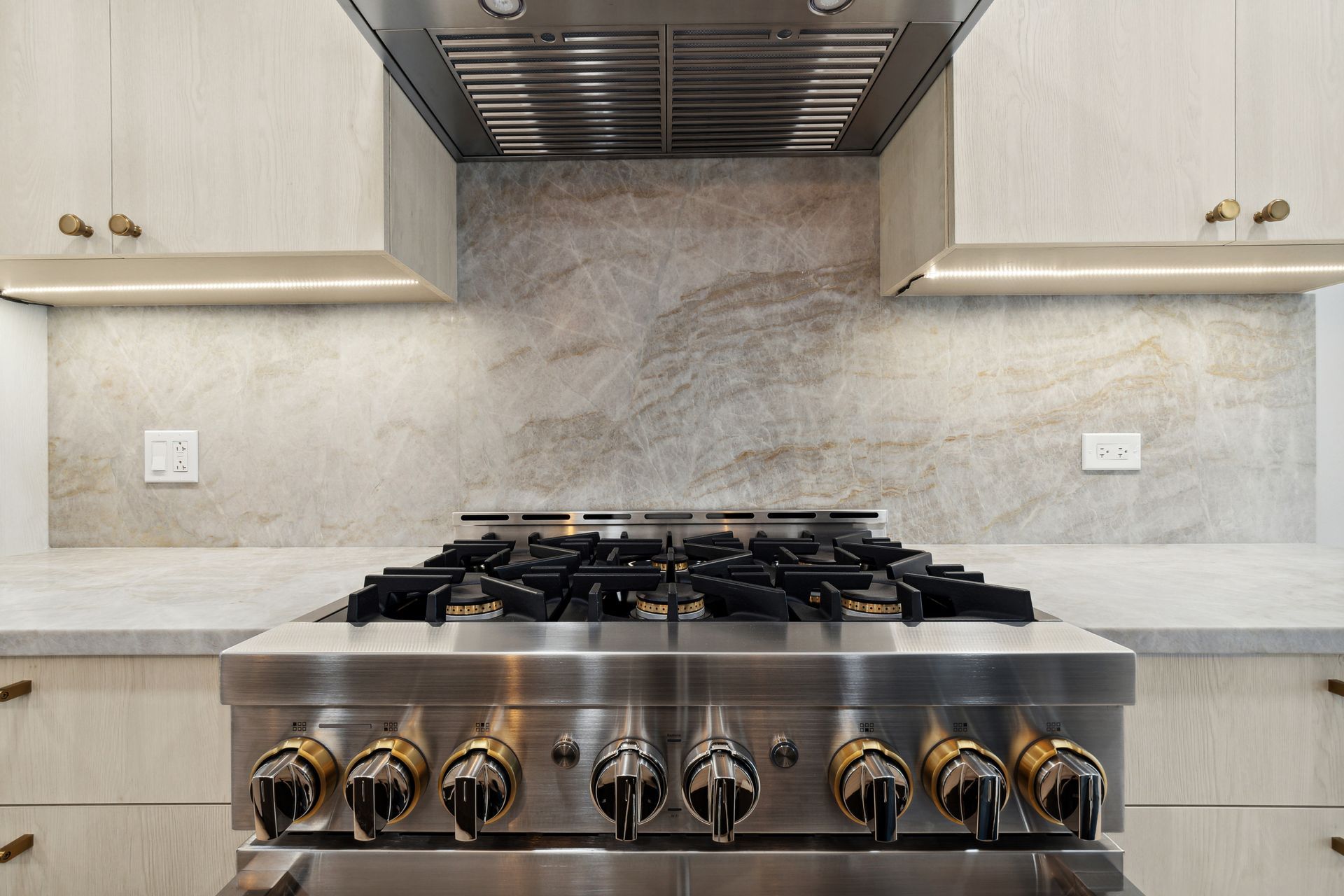 A stainless steel stove with a hood above it in a kitchen.