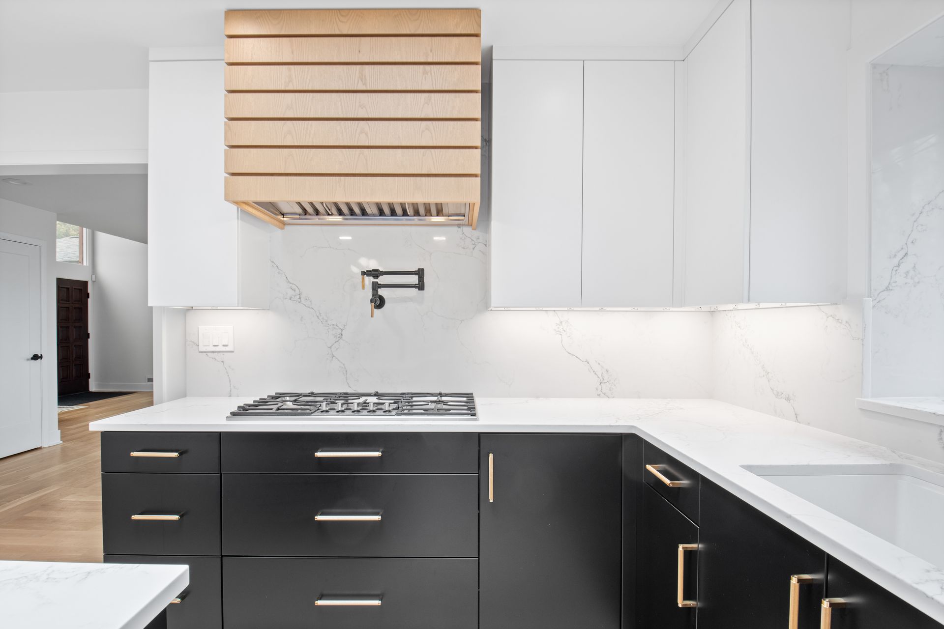 A kitchen with black cabinets and white counter tops and a stove top oven.