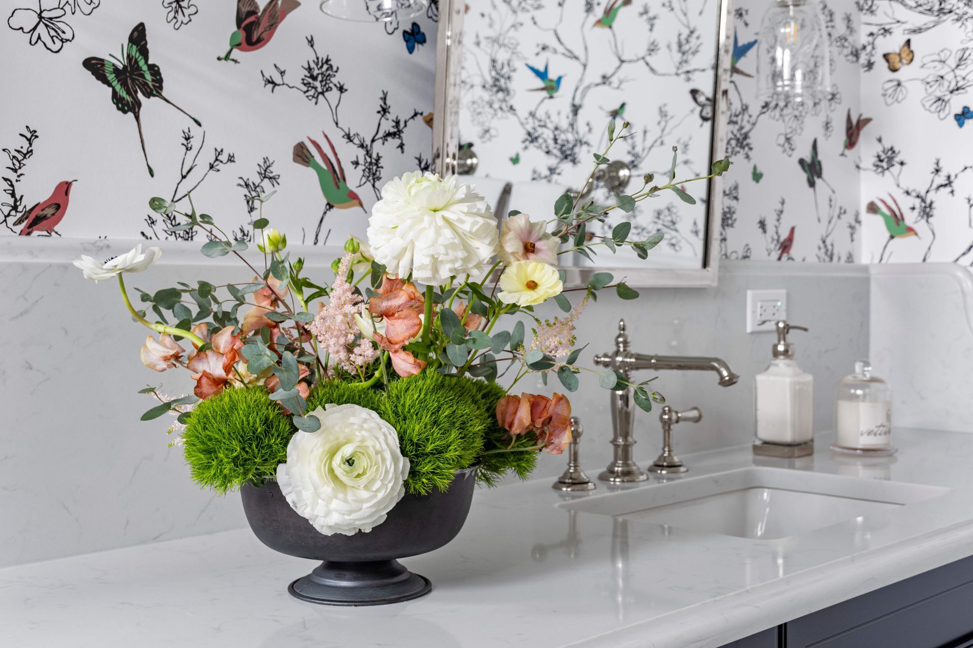 A vase of flowers is sitting on a counter next to a sink.