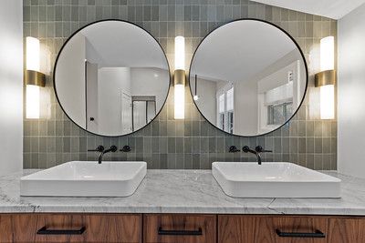 A bathroom with two sinks and two round mirrors.