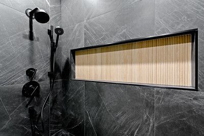 A shower with a black shower head and a wooden niche in the wall.