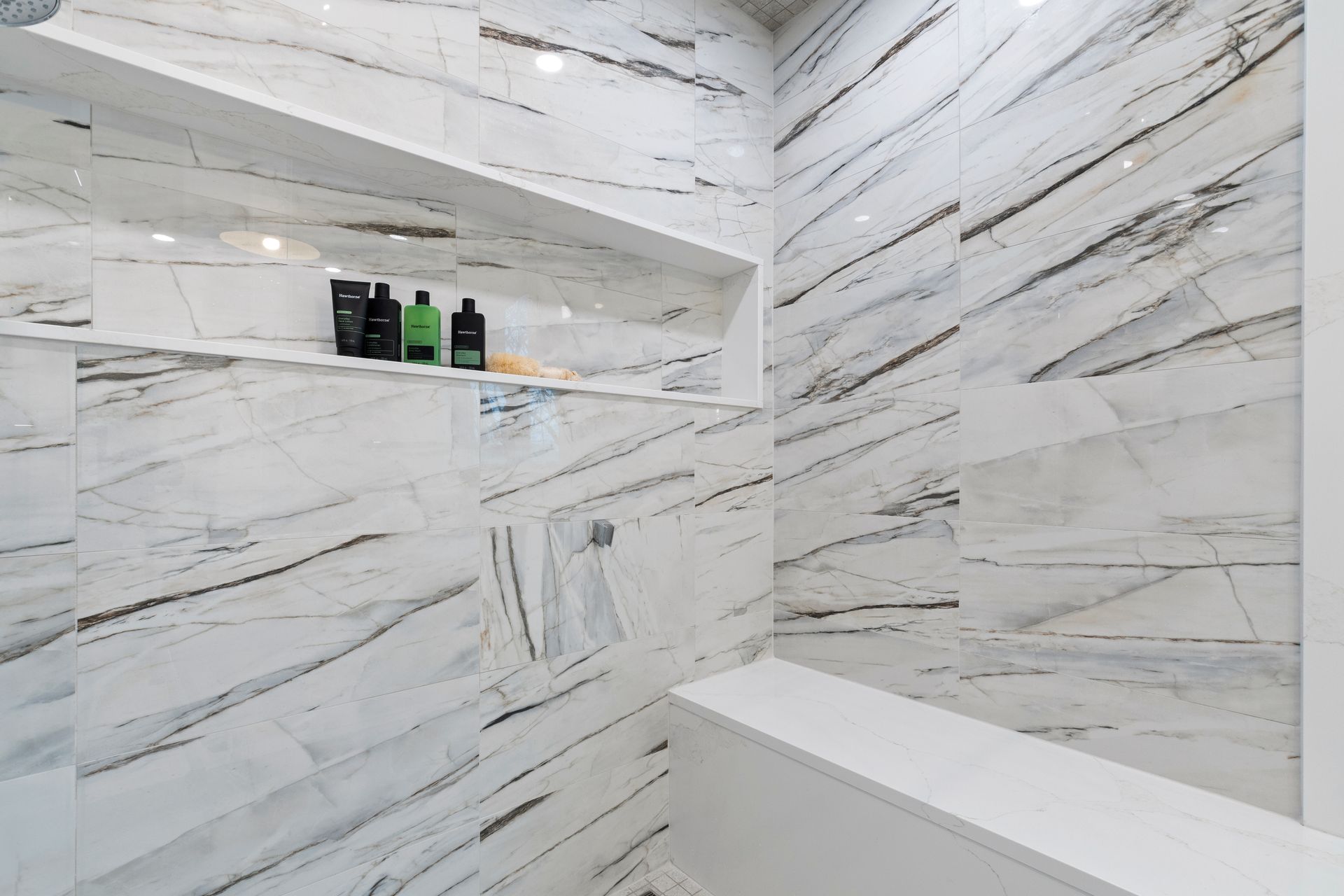A bathroom with marble tiles and a shower with a glass door.