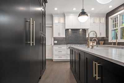 A kitchen with black cabinets and white cabinets and a large island.
