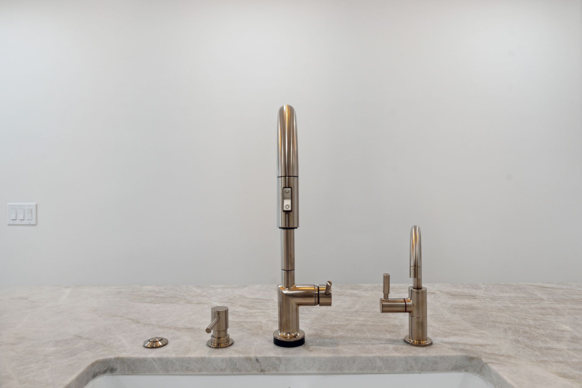 A kitchen sink with two faucets and a soap dispenser.