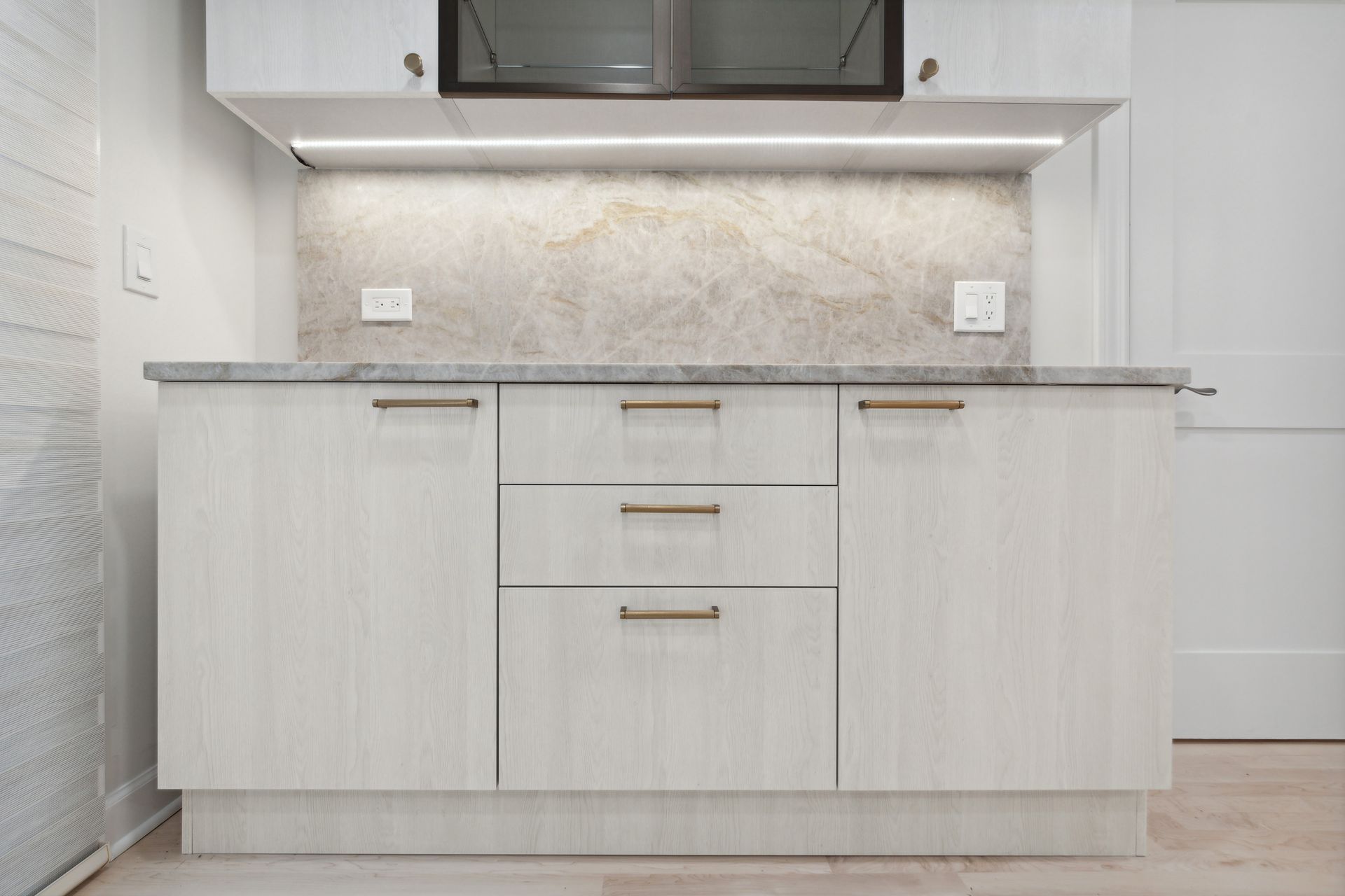 A kitchen with white cabinets and a marble counter top.