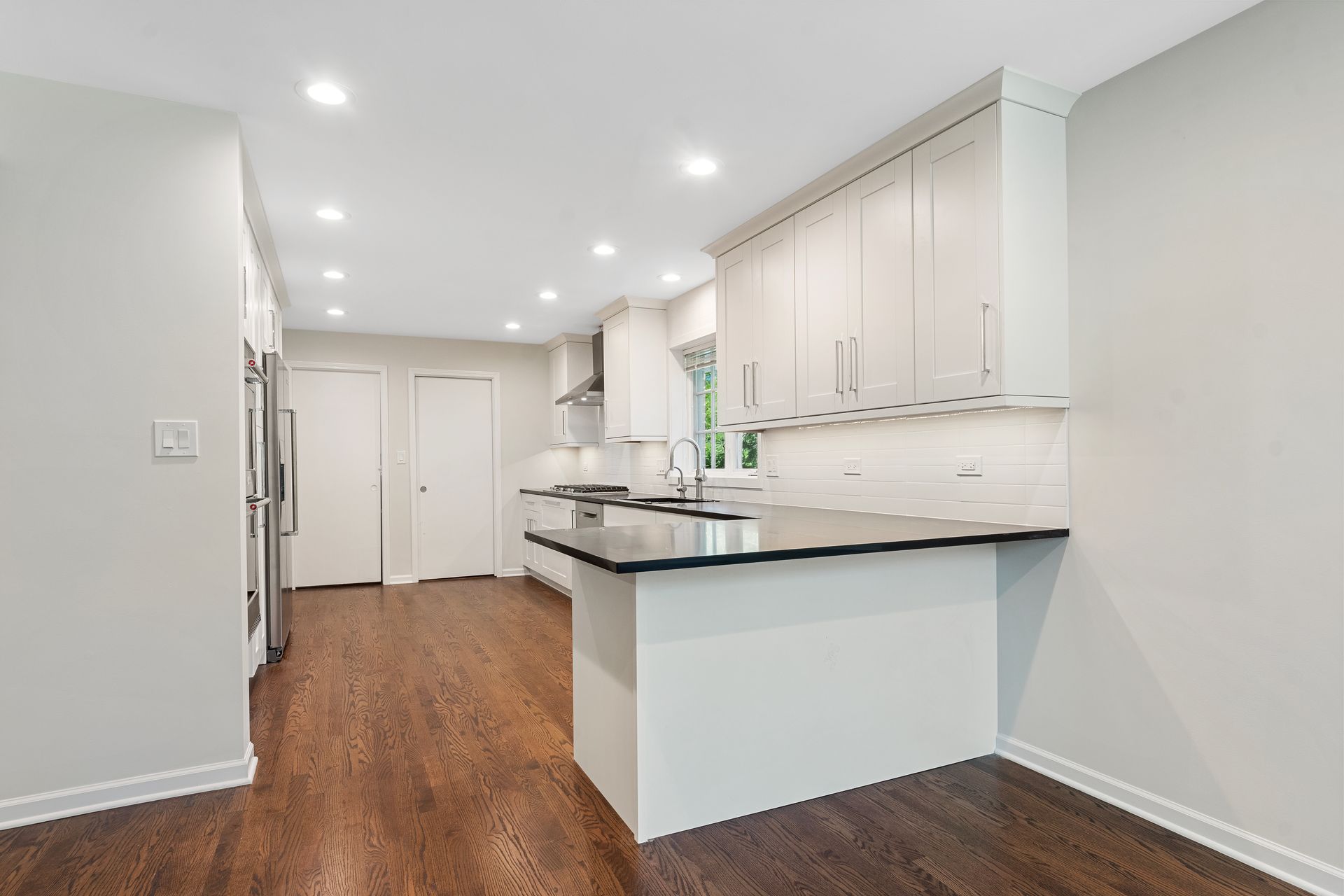 An empty kitchen with white cabinets and a black counter top.