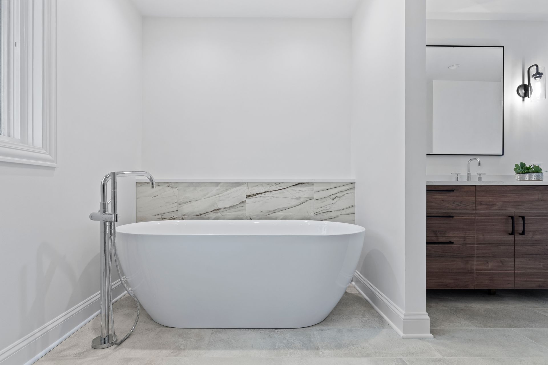 A bathroom with a bathtub , sink and mirror.