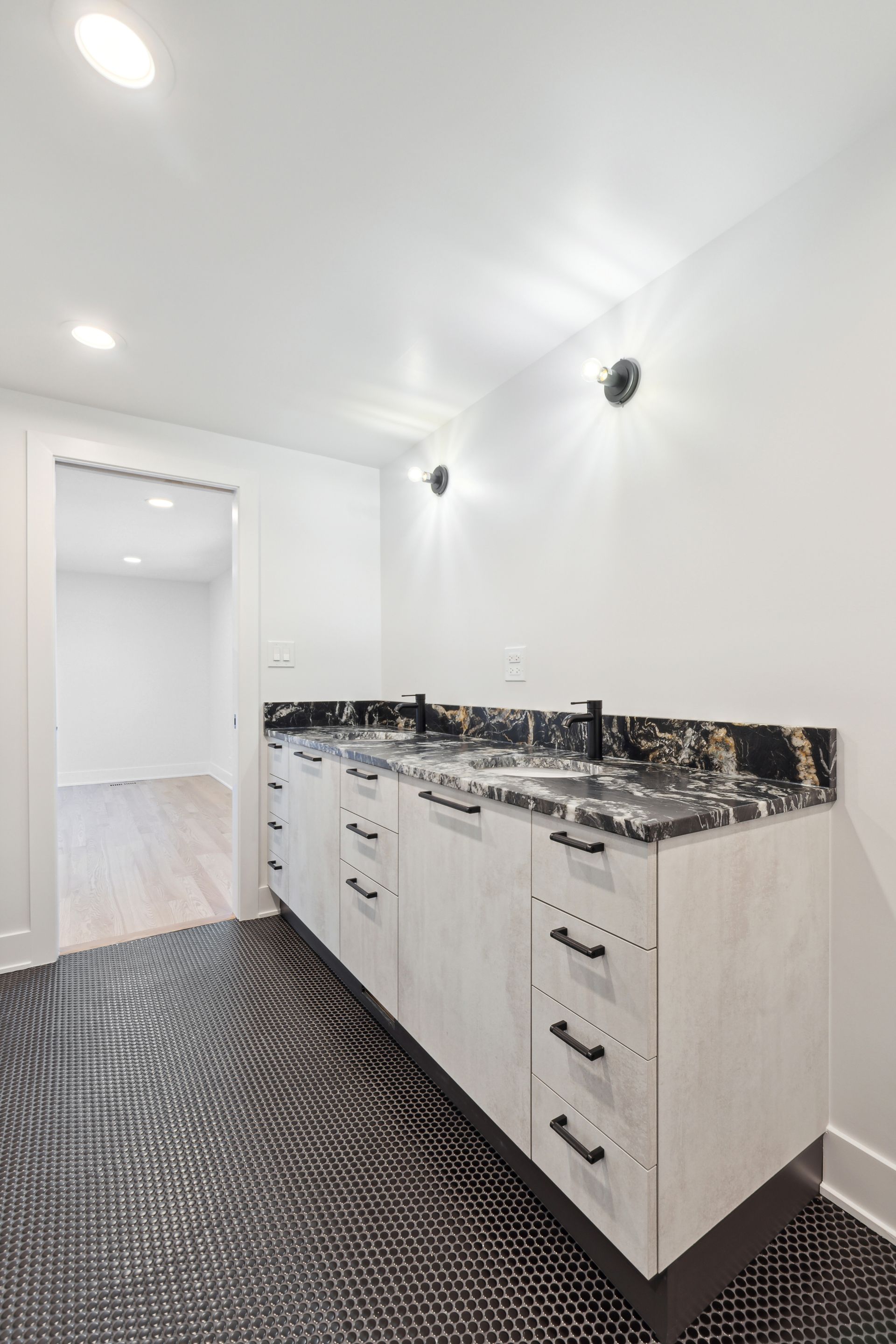A kitchen with white cabinets and black counter tops.