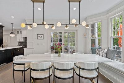 A dining room with a long table and chairs and a chandelier hanging from the ceiling.