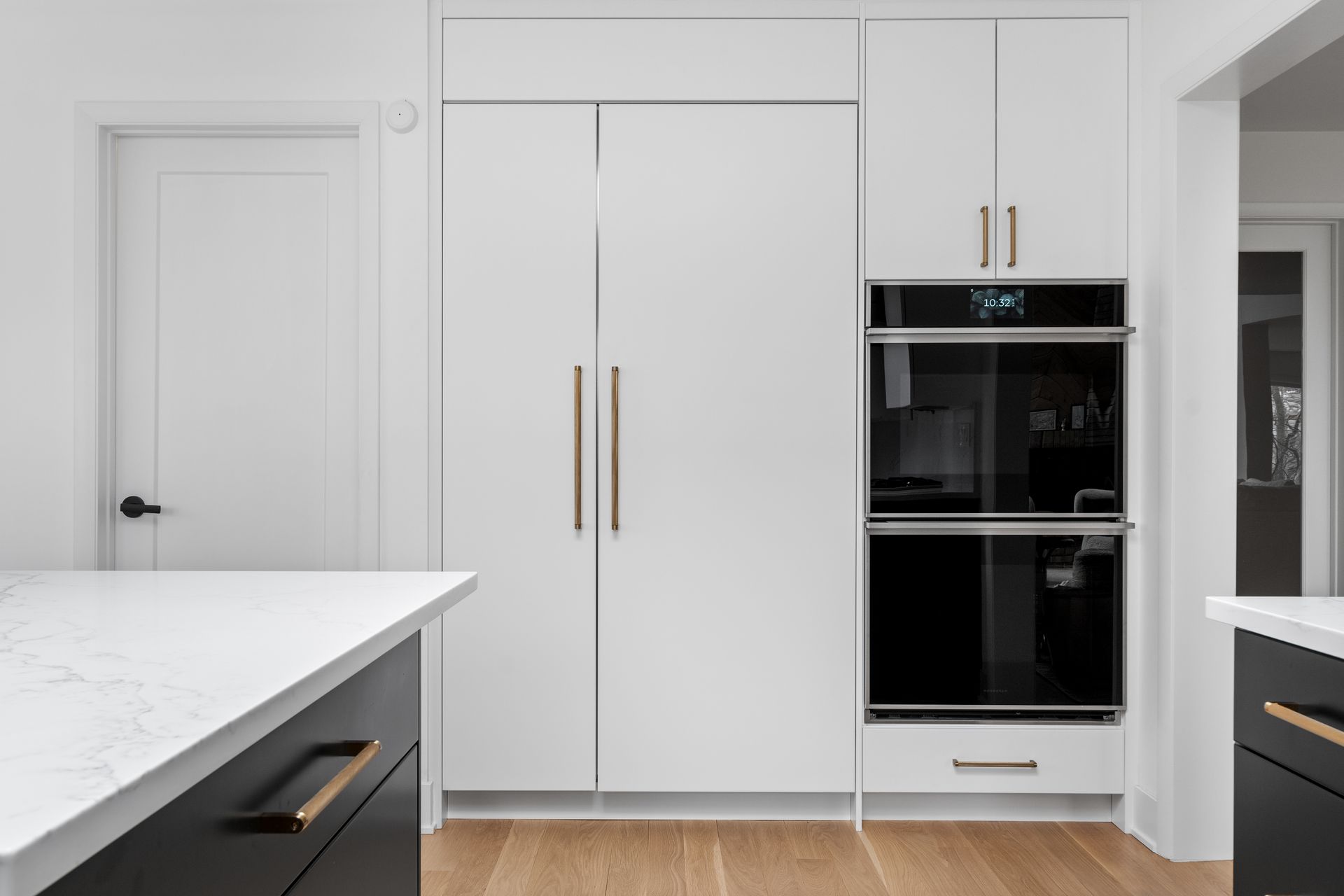 A kitchen with white cabinets , black cabinets and a black oven.