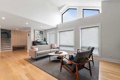 A living room with a couch , chair , coffee table and stairs.