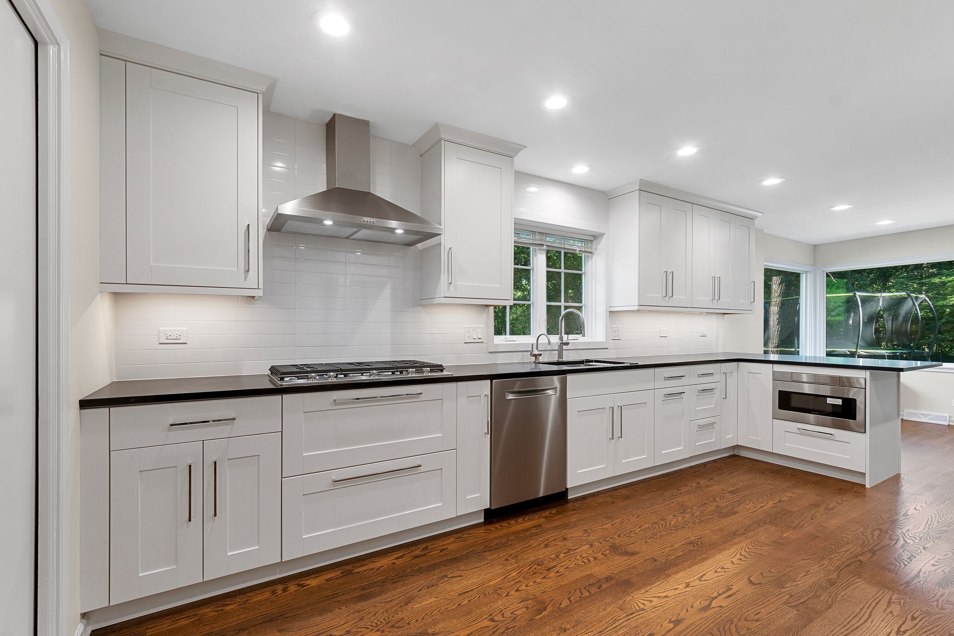 A kitchen with white cabinets , stainless steel appliances , and hardwood floors.