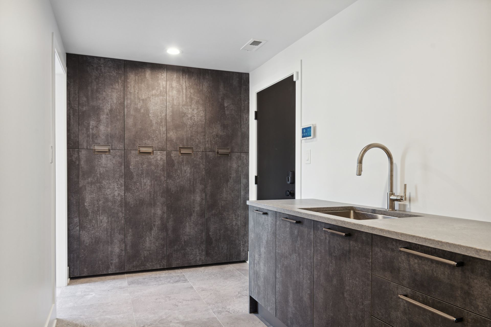 A kitchen with a sink , cabinets , and a door.