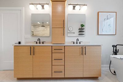 A bathroom with two sinks , two mirrors , and a bathtub.