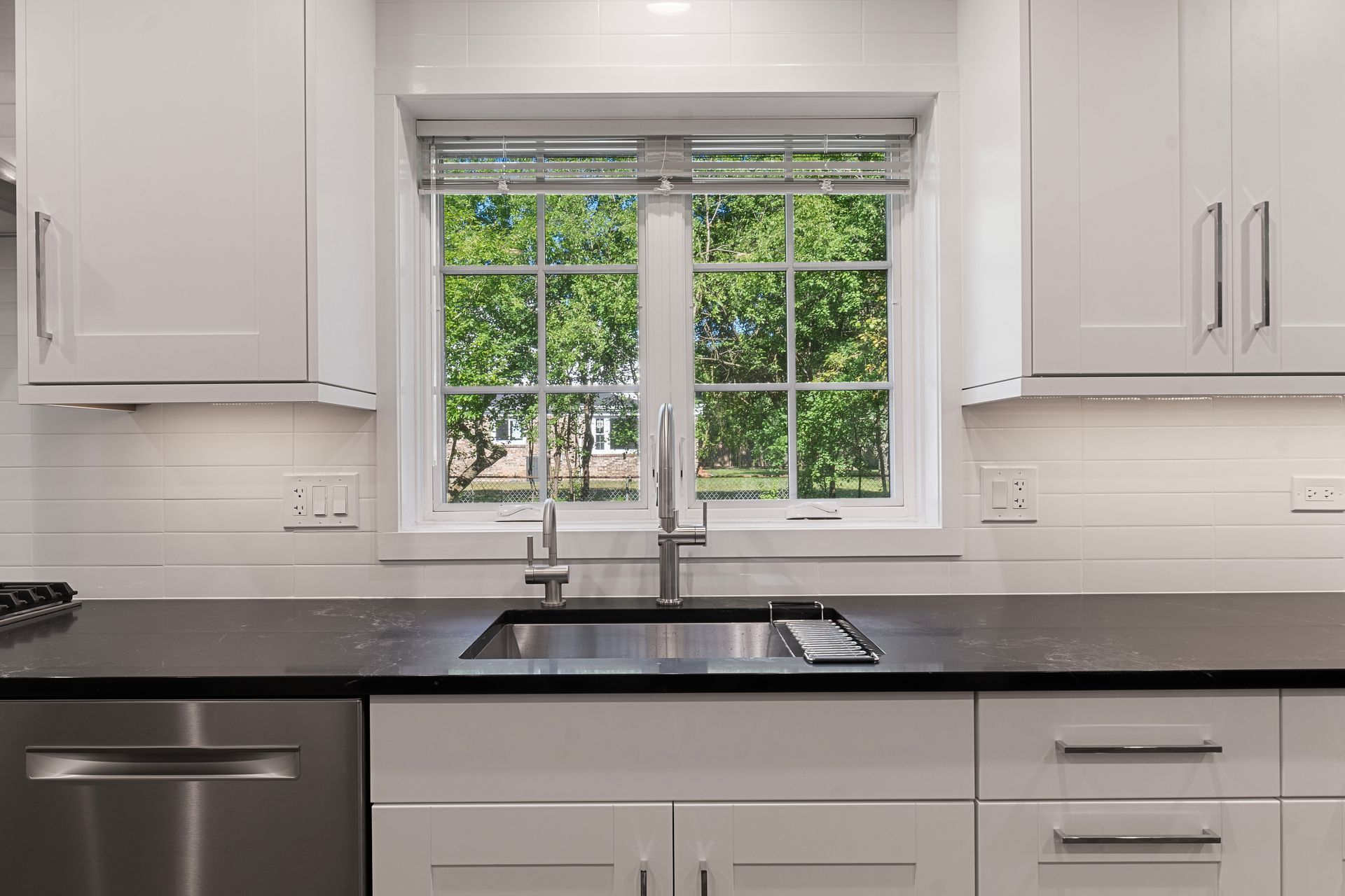 A kitchen with a sink , dishwasher , and window.