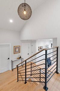 A staircase with a black railing and a light hanging from the ceiling.