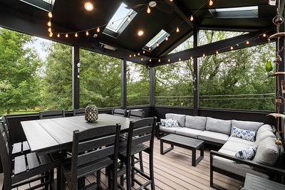 A screened in porch with a table , chairs , and a couch.