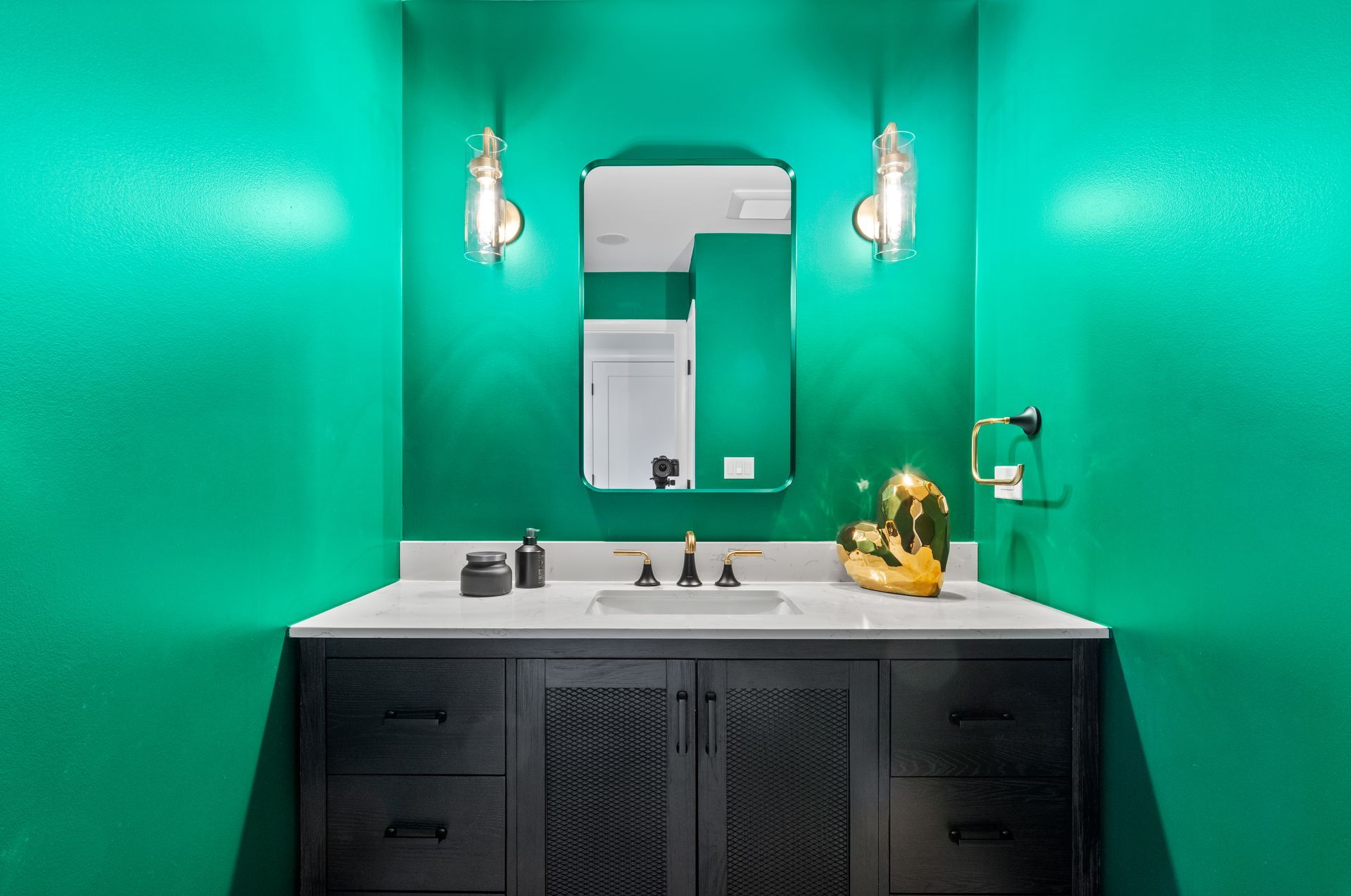 A bathroom with green walls , a sink , and a mirror.