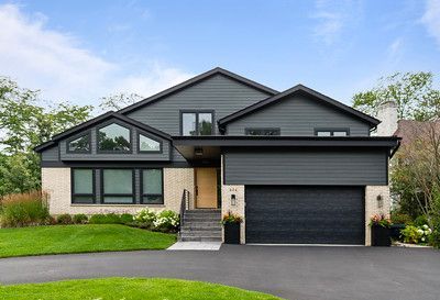 A large house with a black garage door is for sale.