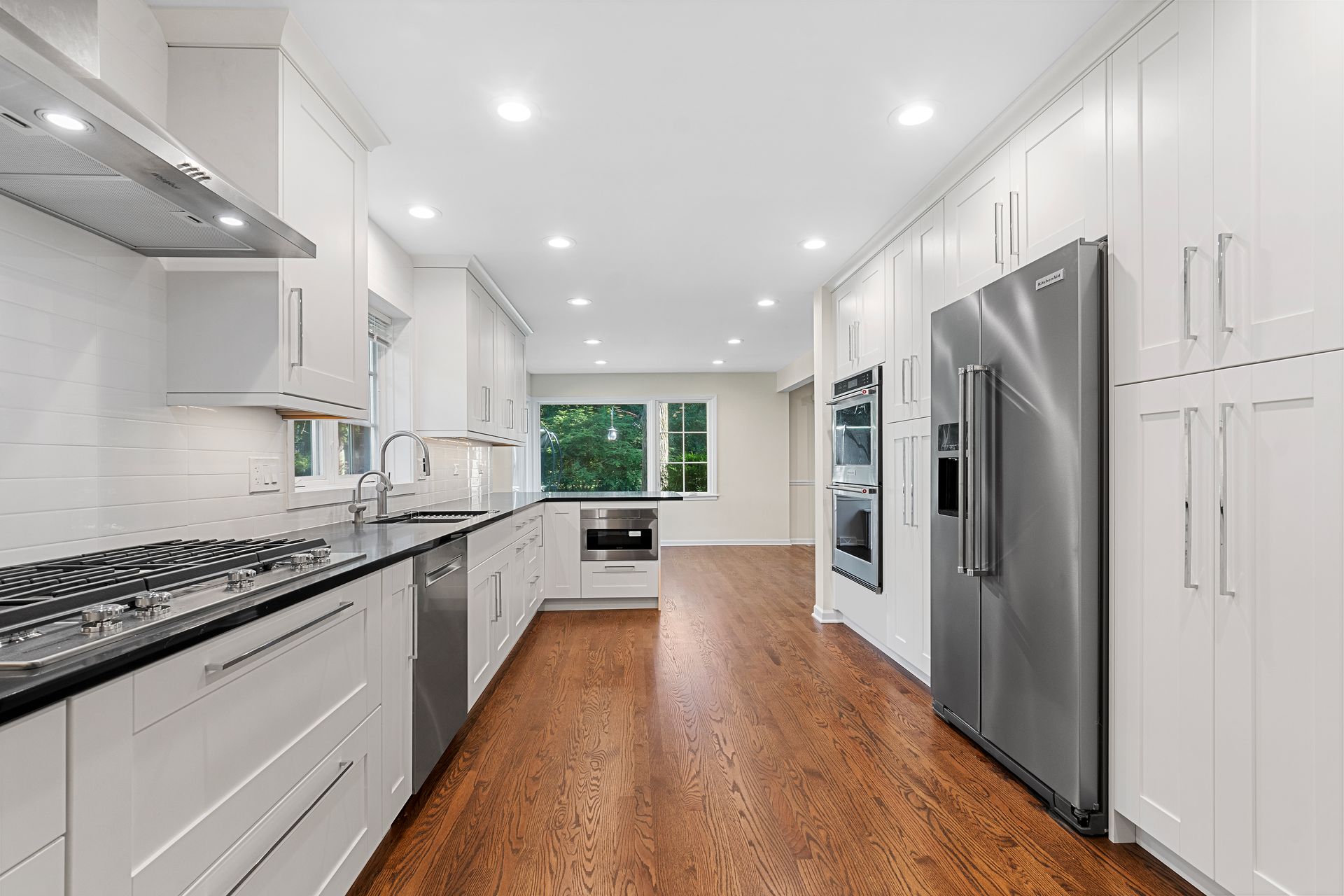 A kitchen with white cabinets , stainless steel appliances , and hardwood floors.