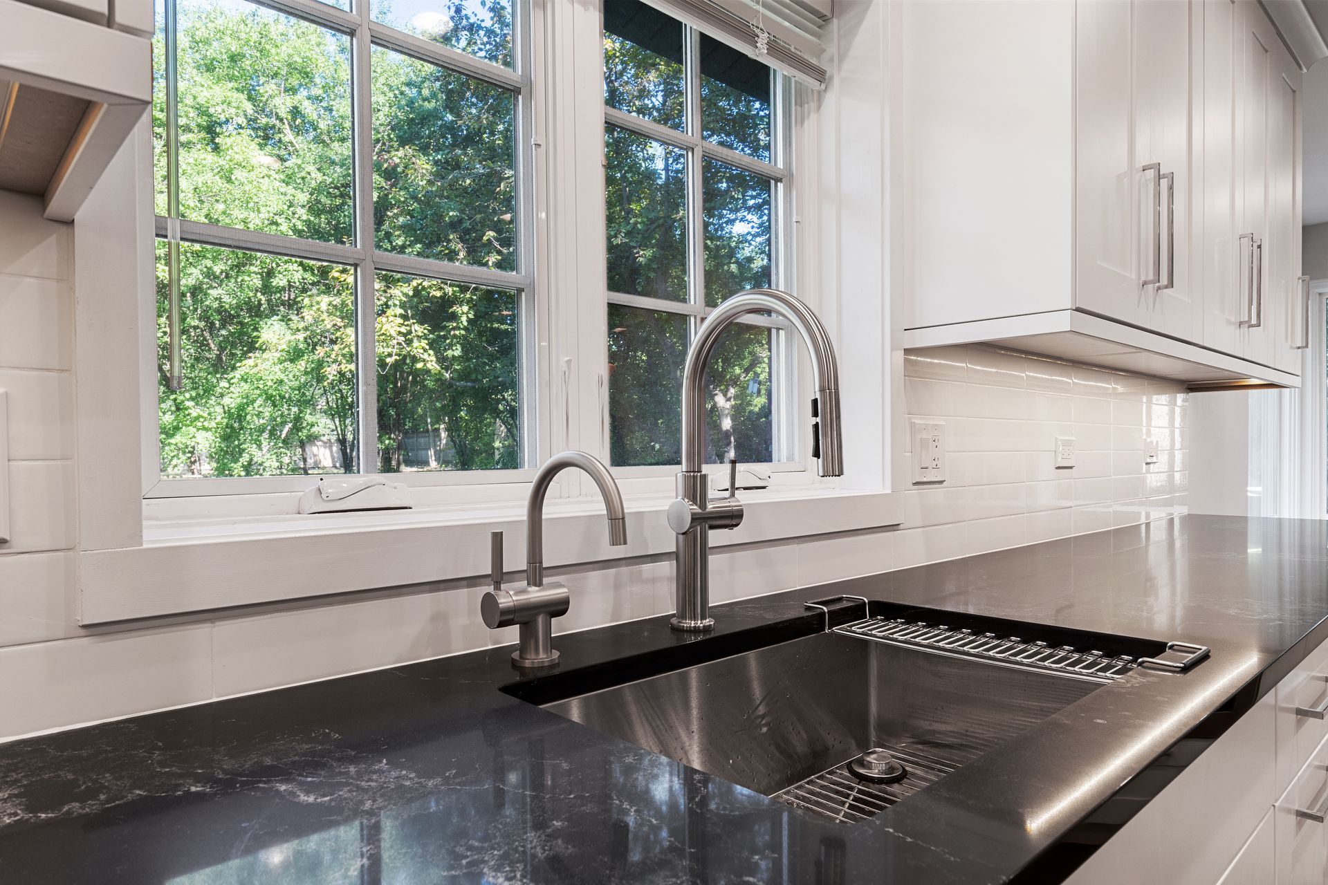 A kitchen with a sink and a window with trees in the background.