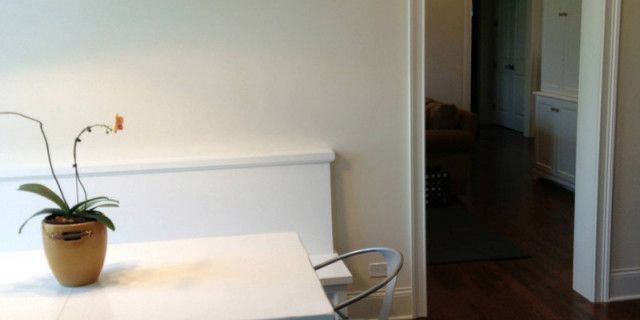 A potted plant is sitting on a white table next to a chair.