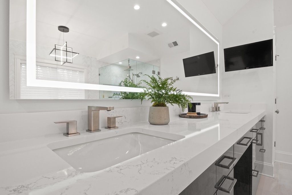 A bathroom with a sink and a large mirror.