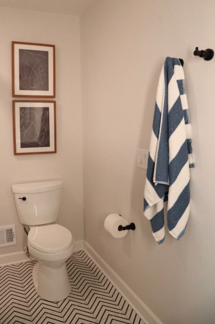 A bathroom with a toilet and a towel hanging on the wall