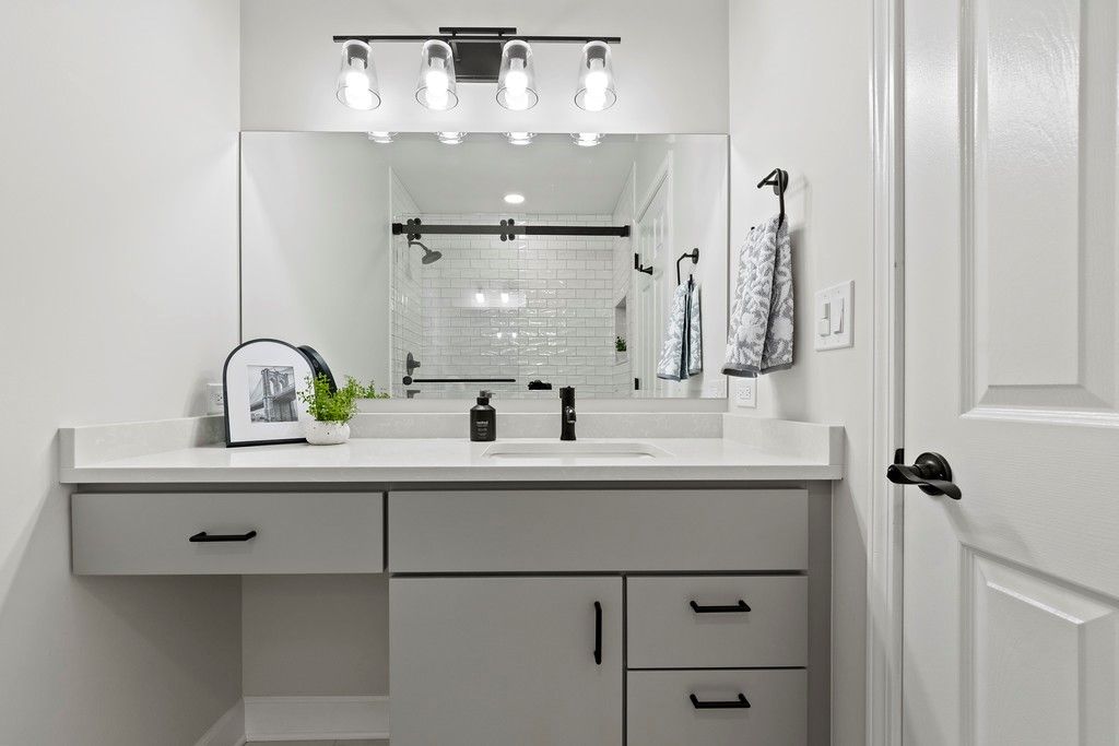 A bathroom with a sink , mirror and drawers.