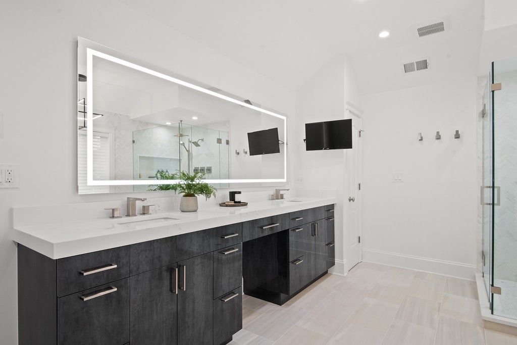 A bathroom with two sinks , a large mirror and a walk in shower.