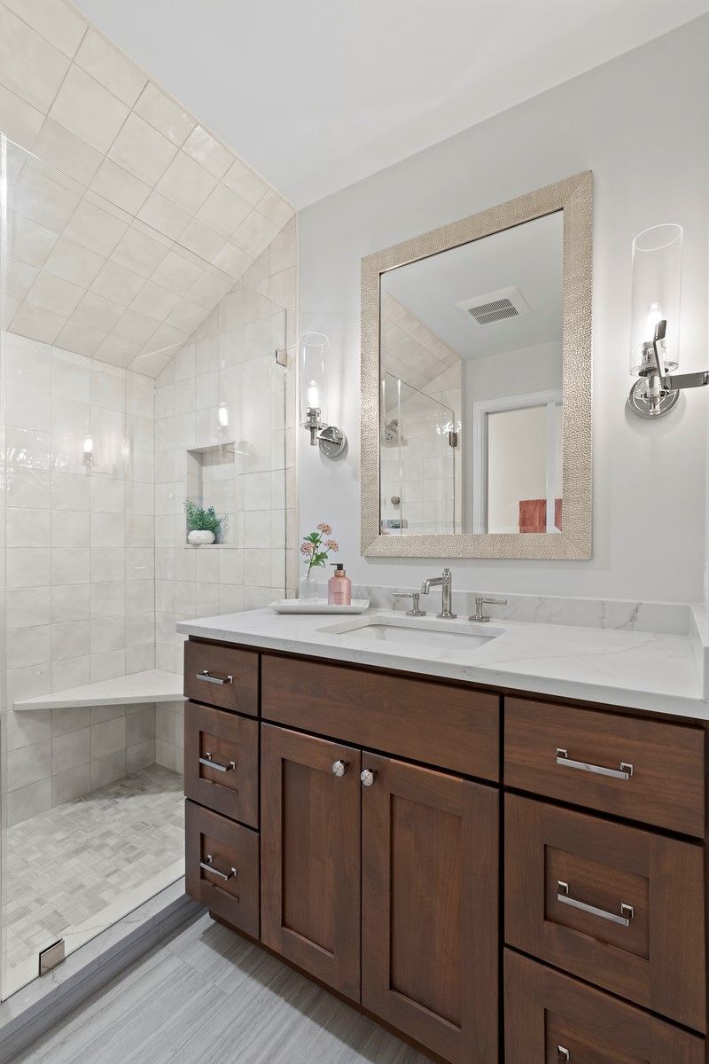 A bathroom with a sink , mirror and shower.