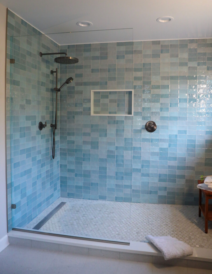 A bathroom with blue tiles and a walk in shower.