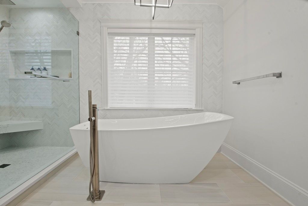 A bathroom with a bathtub , shower , and window.