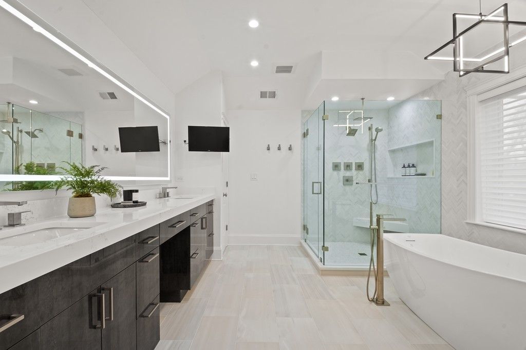 A bathroom with a bathtub , sink , shower and mirror.