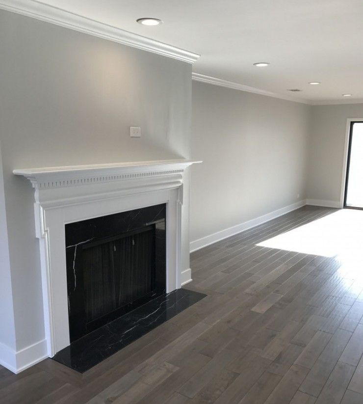 An empty living room with a fireplace and hardwood floors.